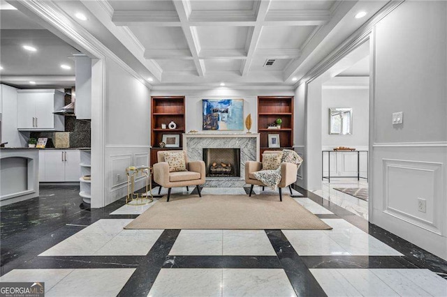 living area with a decorative wall, wainscoting, a high end fireplace, ornamental molding, and recessed lighting