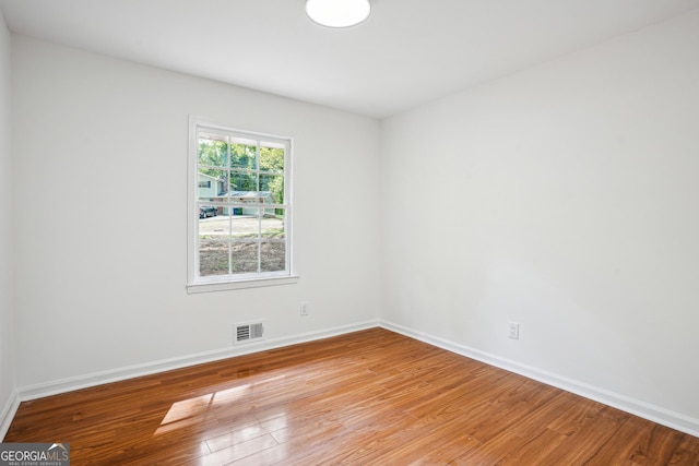 unfurnished room featuring light wood-type flooring, visible vents, and baseboards