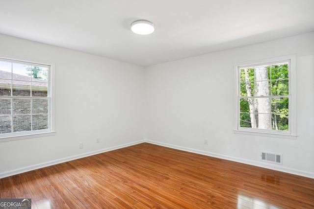 spare room with baseboards, hardwood / wood-style floors, and visible vents