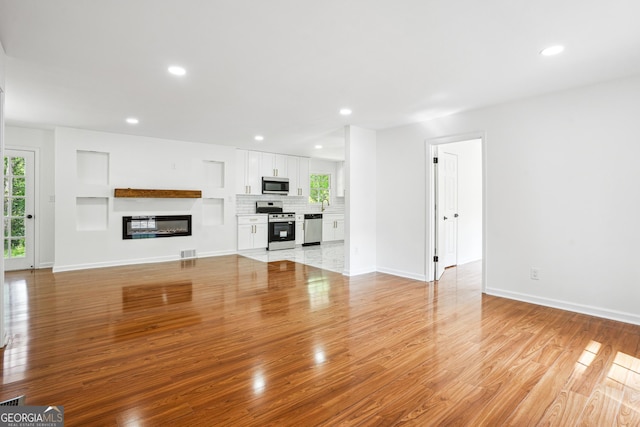 unfurnished living room with light wood-type flooring, visible vents, recessed lighting, and a healthy amount of sunlight