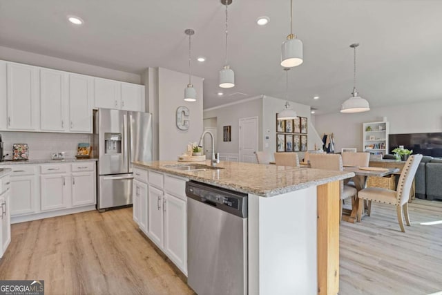 kitchen with light wood-style flooring, appliances with stainless steel finishes, open floor plan, and a sink