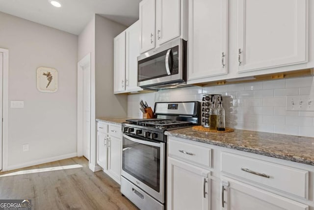 kitchen featuring white cabinets, appliances with stainless steel finishes, and decorative backsplash