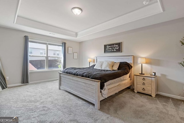 carpeted bedroom with baseboards and a raised ceiling