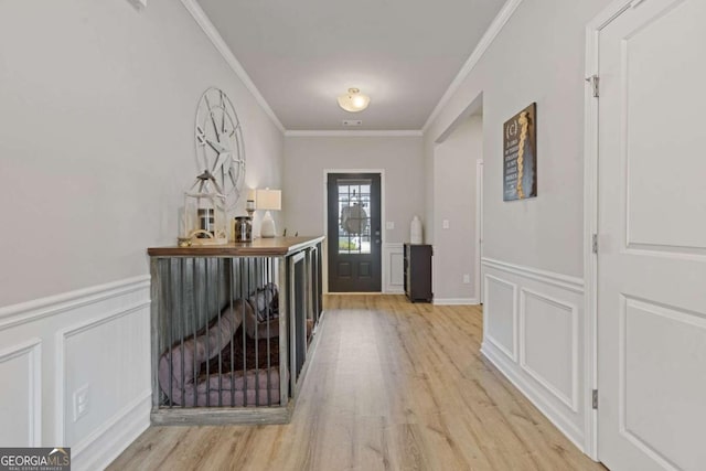 foyer featuring a decorative wall, ornamental molding, and light wood-style floors