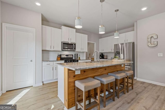kitchen with a breakfast bar area, light wood-style flooring, stainless steel appliances, and a sink