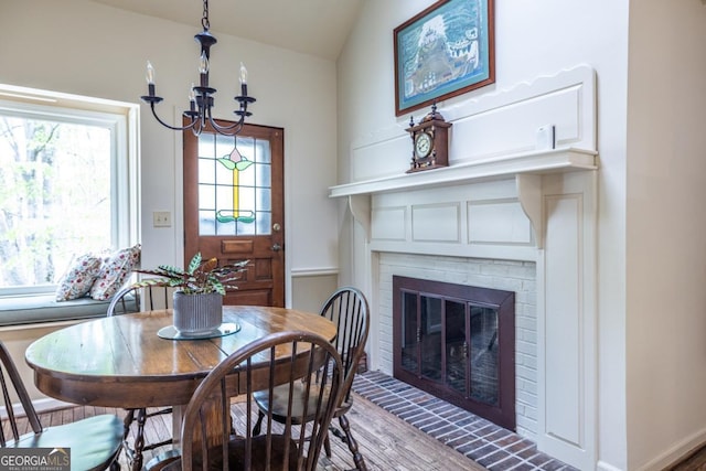 dining area with vaulted ceiling, a fireplace, and a chandelier