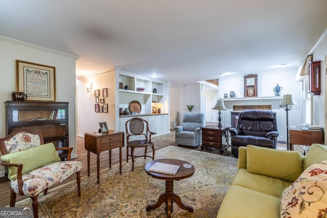 living area with a fireplace, wood finished floors, and ornamental molding
