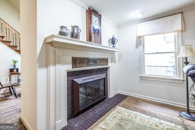 interior space with stairway, wood finished floors, crown molding, baseboards, and a glass covered fireplace
