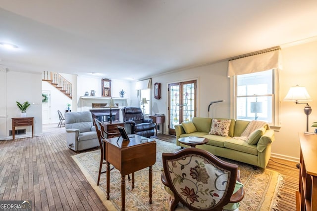 living room with wood-type flooring, crown molding, and stairs