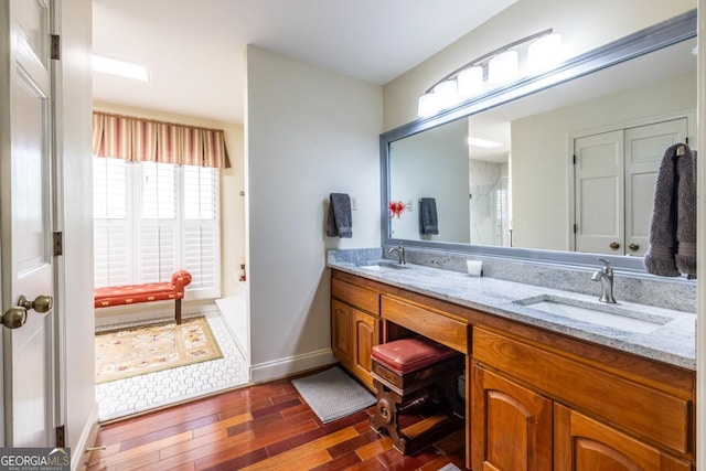 full bath featuring wood finished floors, a sink, and double vanity