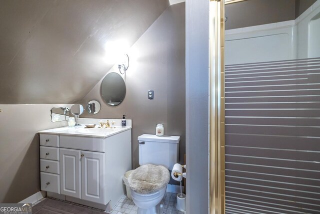bathroom with toilet, tile patterned floors, vanity, and vaulted ceiling
