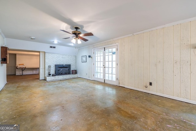 unfurnished living room with visible vents, baseboards, a ceiling fan, concrete flooring, and wooden walls