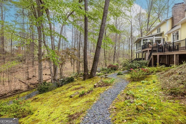 view of yard with a wooden deck, a sunroom, and stairway