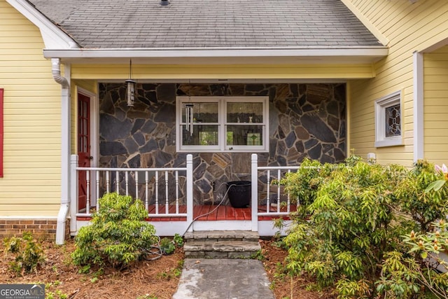 property entrance featuring stone siding and a shingled roof