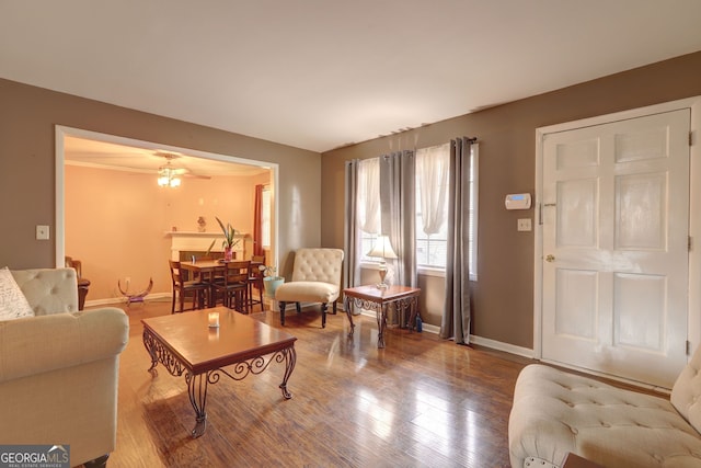living room with ceiling fan, baseboards, and wood finished floors