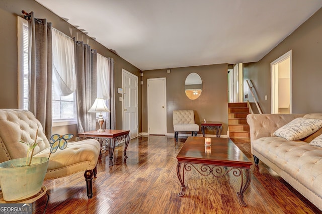 living area featuring wood finished floors, baseboards, and stairway