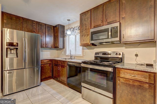 kitchen with light stone counters, hanging light fixtures, a sink, light tile patterned floors, and stainless steel appliances