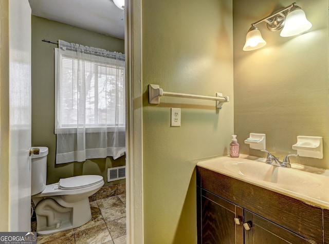 half bath with visible vents, stone finish flooring, vanity, and toilet