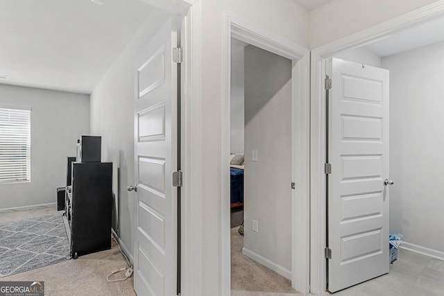 hallway featuring baseboards and light colored carpet