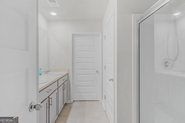 full bathroom featuring double vanity, visible vents, a stall shower, and a sink