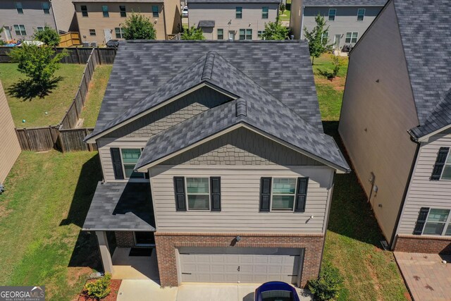 view of front of property with an attached garage, a shingled roof, fence, and brick siding