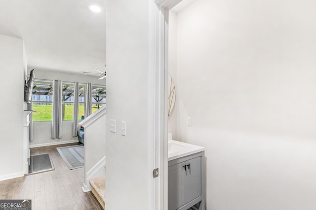 hallway with recessed lighting, stairs, wood finished floors, and baseboards