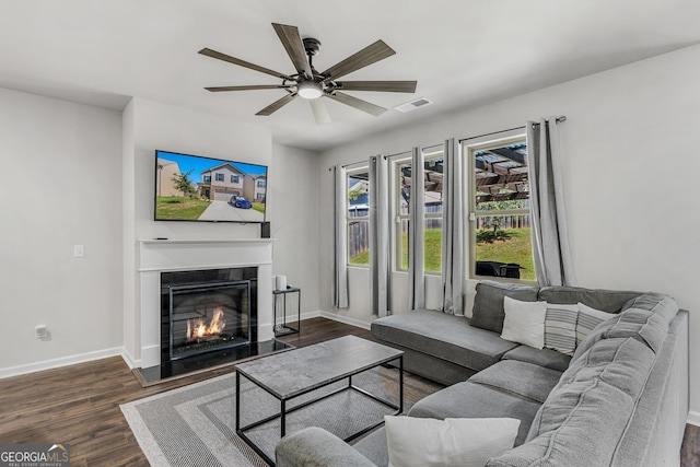 living area with a glass covered fireplace, baseboards, visible vents, and dark wood-style flooring