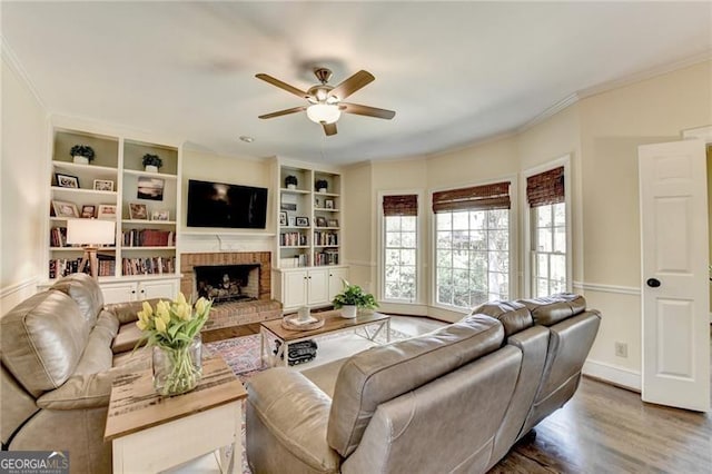 living area with baseboards, a ceiling fan, wood finished floors, and crown molding