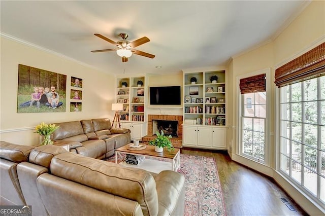 living room featuring a ceiling fan, dark wood-style flooring, ornamental molding, and a healthy amount of sunlight