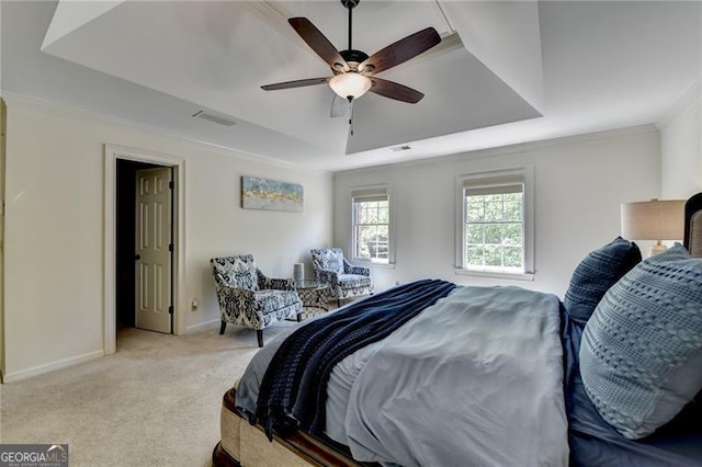 carpeted bedroom featuring baseboards, crown molding, a tray ceiling, and visible vents