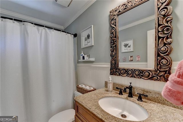 bathroom with a wainscoted wall, toilet, curtained shower, vanity, and ornamental molding