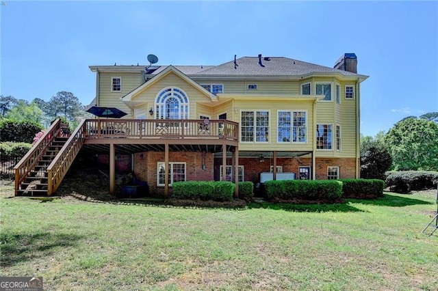rear view of house featuring a wooden deck, a yard, brick siding, and a chimney