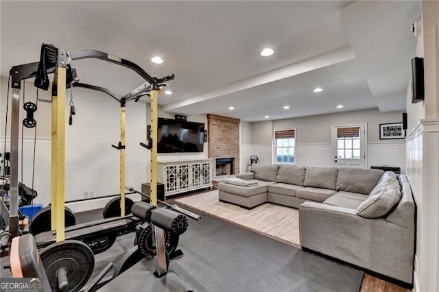 workout room with recessed lighting, a stone fireplace, and wainscoting