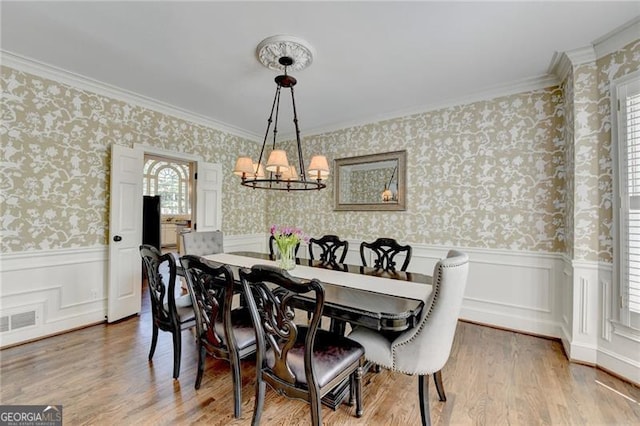 dining area with a chandelier, wallpapered walls, visible vents, and a wainscoted wall
