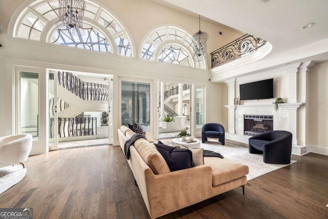 3511 Roxboro Rd NE, Atlanta, GA 30326 - living room featuring wood finished floors, a fireplace with raised hearth, stairs, an inviting chandelier, and a towering ceiling