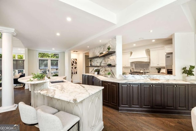 3511 Roxboro Rd NE, Atlanta, GA 30326 - kitchen featuring light stone counters, custom exhaust hood, open shelves, a sink, and decorative backsplash