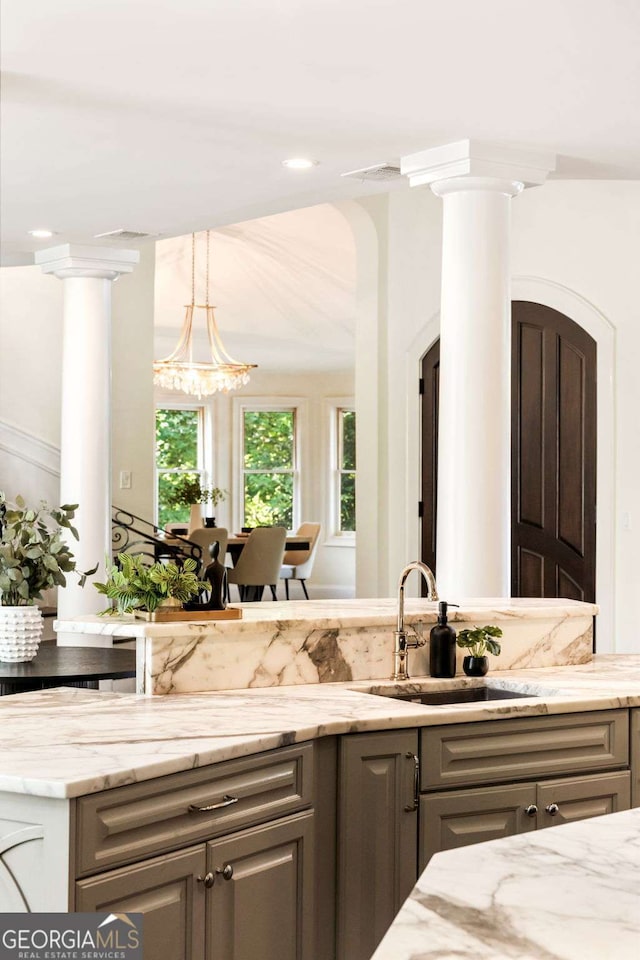 3511 Roxboro Rd NE, Atlanta, GA 30326 - kitchen with decorative columns, a sink, and light stone counters