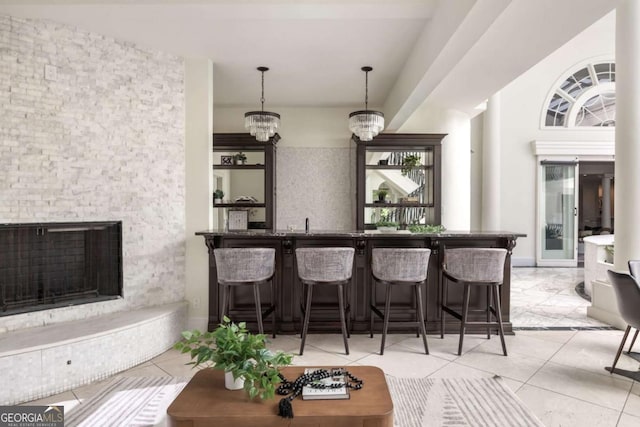 3511 Roxboro Rd NE, Atlanta, GA 30326 - bar featuring bar area, an inviting chandelier, a fireplace with raised hearth, and light tile patterned floors