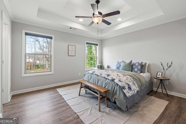 bedroom featuring wood finished floors, a tray ceiling, ornamental molding, visible vents, and recessed lighting