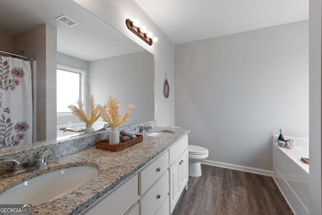 bathroom with wood finished floors, visible vents, a sink, and double vanity