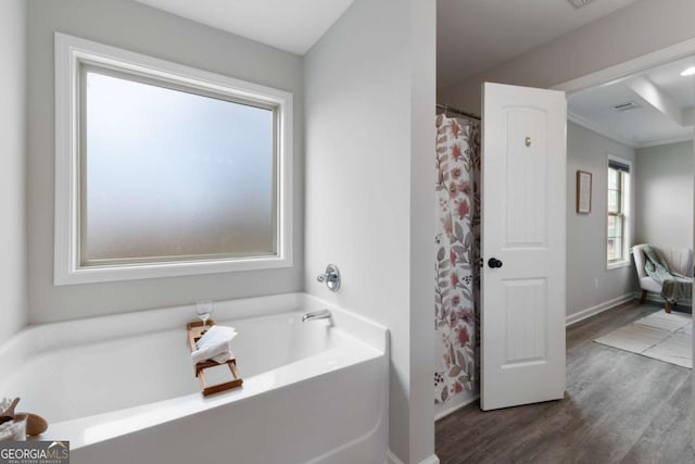full bathroom featuring wood finished floors, a garden tub, baseboards, and ornamental molding