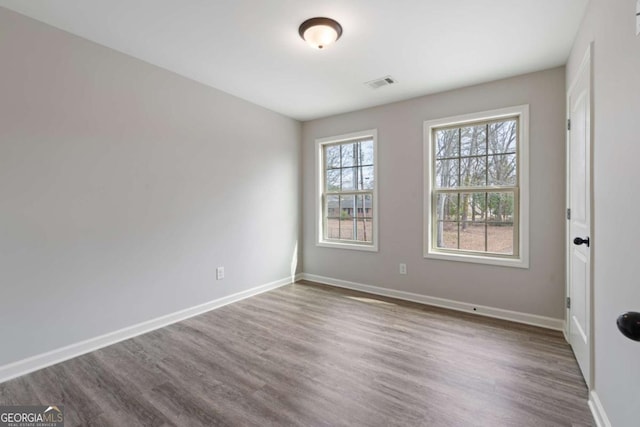 empty room with baseboards, dark wood-style flooring, and visible vents