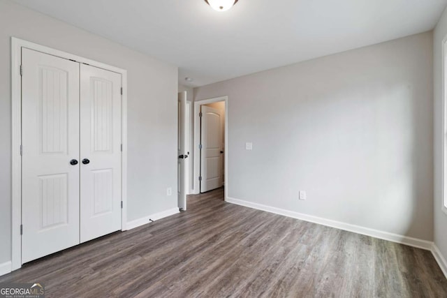 unfurnished bedroom with baseboards, wood finished floors, and a closet