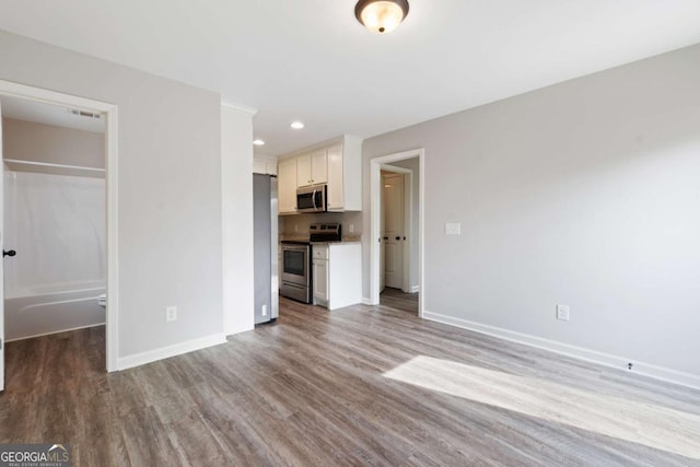 unfurnished living room with recessed lighting, wood finished floors, visible vents, and baseboards