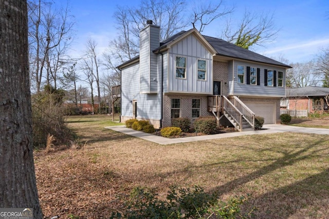split foyer home featuring a front lawn, a chimney, concrete driveway, brick siding, and board and batten siding
