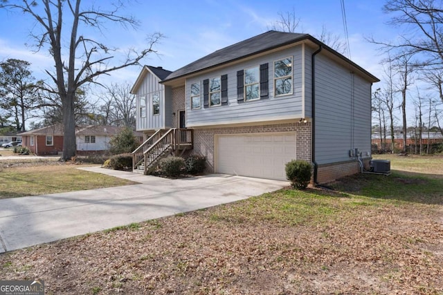 bi-level home featuring a front lawn, cooling unit, concrete driveway, brick siding, and a garage