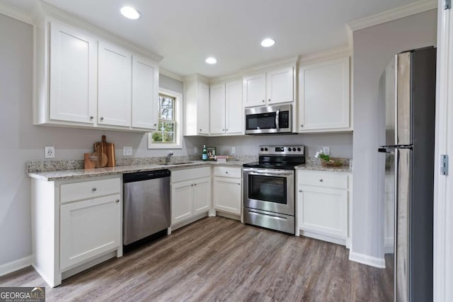 kitchen featuring light wood-type flooring, ornamental molding, white cabinets, and appliances with stainless steel finishes