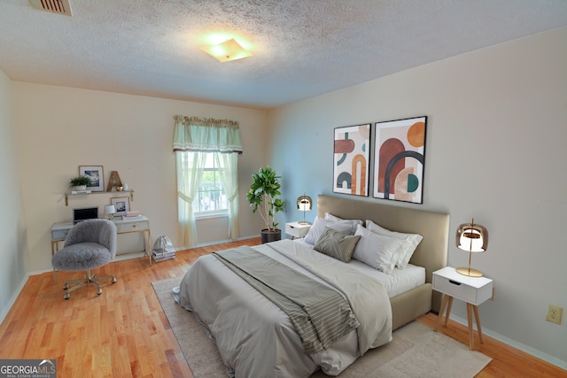 1005 Berkeley Woods Dr, Duluth, GA 30096 - bedroom with wood finished floors, a textured ceiling, and baseboards