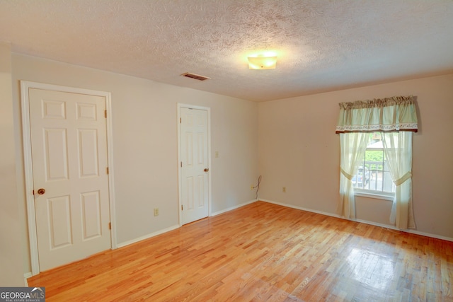 1005 Berkeley Woods Dr, Duluth, GA 30096 - unfurnished room with light wood-style floors, a textured ceiling, and baseboards