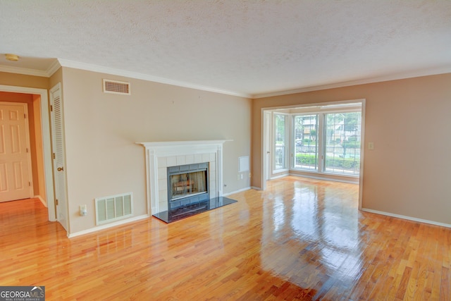 1005 Berkeley Woods Dr, Duluth, GA 30096 - unfurnished living room with wood finished floors, baseboards, a tile fireplace, crown molding, and a textured ceiling